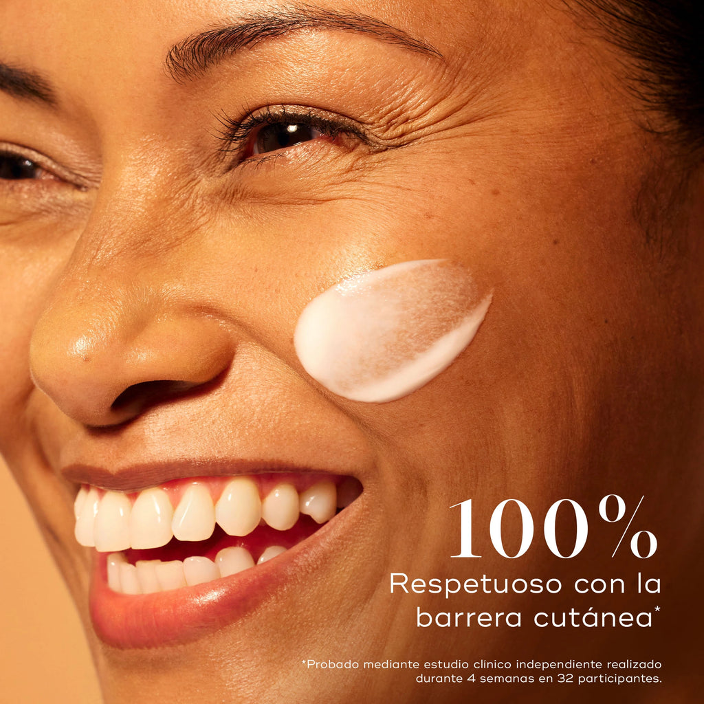 Mujer sonriente con la piel radiante y una pasada de suero Medik8 C-Tetra Advanced en la mejilla, destacando la alteración de la barrera 0% para una luminosidad suave pero eficaz.