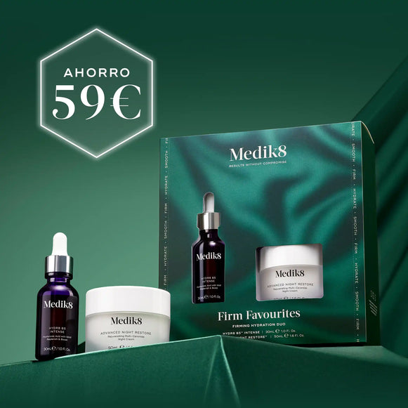 Tres productos para el cuidado de la piel de Medik8 (un frasco cuentagotas oscuro, un tarro de crema blanco y un tubo blanco) dispuestos sobre un fondo verde oscuro con textura, con una caja de producto abierta visible detrás de ellos. En la esquina superior izquierda se muestra de forma destacada un hexágono blanco con el texto «AHORRO 59€».-2