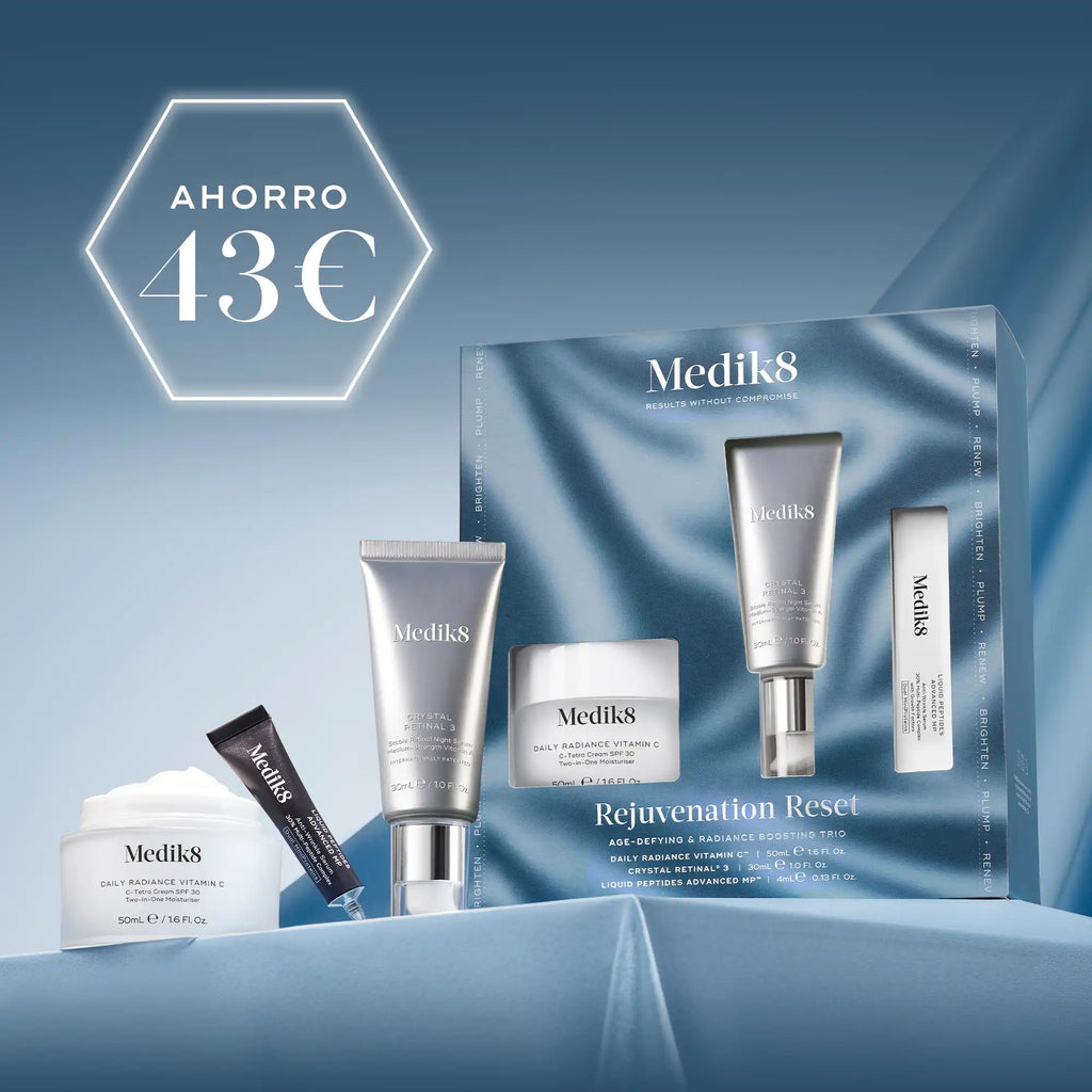 Tres productos para el cuidado de la piel de Medik8, incluyendo un tarro blanco, un frasco con dosificador plateado y un tubo negro, dispuestos sobre un fondo de tela ondulada de color azul claro. En la esquina superior izquierda se muestra de forma destacada un círculo blanco con el texto «AHORRO 43€»