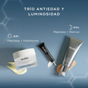 Tres productos para el cuidado de la piel de Medik8, un frasco blanco, un tubo negro y un frasco con dosificador plateado, dispuestos sobre un fondo de tela ondulado de color azul claro. El texto "TRÍO ANTIEDAD Y LUMINOSIDAD" aparece en la parte superior, con un texto más pequeño debajo: "Péptidos + Hidratante" y "RETINAL"