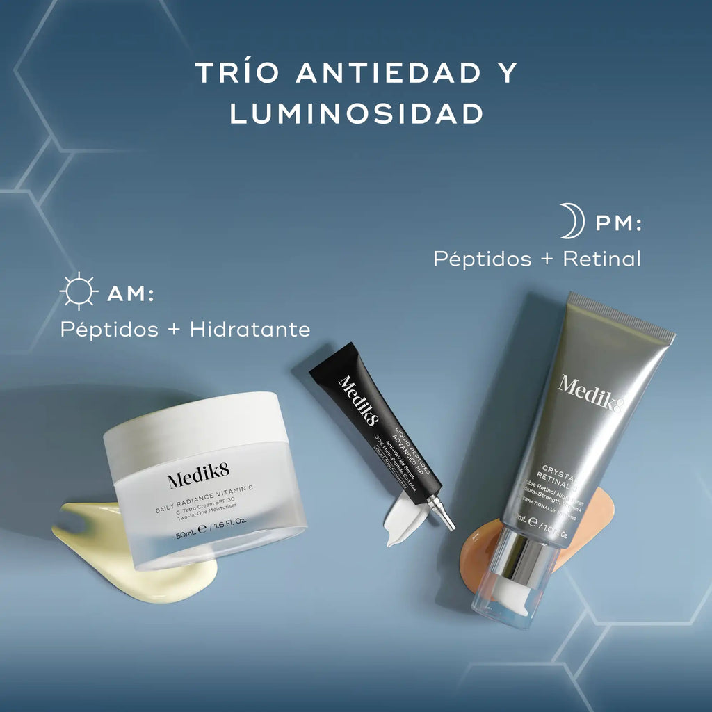 Tres productos para el cuidado de la piel de Medik8, un frasco blanco, un tubo negro y un frasco con dosificador plateado, dispuestos sobre un fondo de tela ondulado de color azul claro. El texto "TRÍO ANTIEDAD Y LUMINOSIDAD" aparece en la parte superior, con un texto más pequeño debajo: "Péptidos + Hidratante" y "RETINAL"