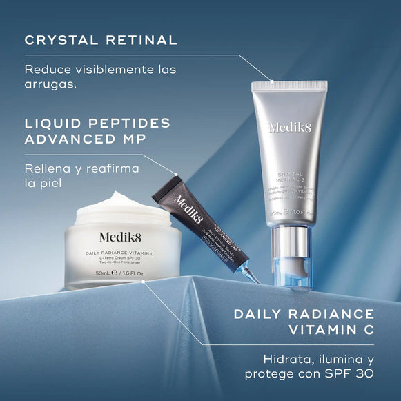 Dos conjuntos distintos de productos para el cuidado de la piel de Medik8 expuestos sobre un fondo de tela ondulada de color azul claro. A la izquierda, se muestran un frasco blanco y un tubo plateado bajo el título «CRYSTAL RETINAL» con la descripción «Reduce visiblemente las arrugas». A la derecha, se muestran un frasco con dosificador negro y un tubo blanco bajo el título «DAILY RADIANCE VITAMIN C» con la descripción «Hidrata, ilumina y protege con SPF 30».-hover-3
